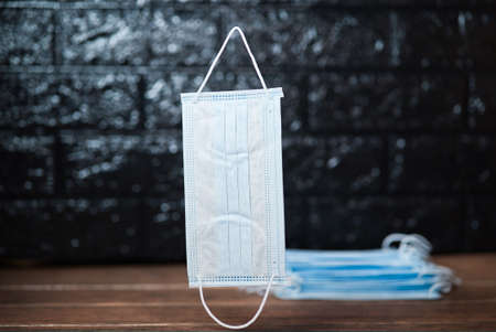 Disposable surgical face masks with ear-loop falling down with many mask in backgroundの写真素材