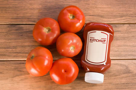 ketchup sauce with many tomatoes around on brown wooden boardの写真素材