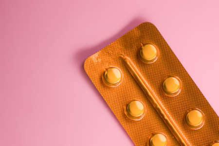 half a blister pack of pills top view with a pink backgroundの写真素材