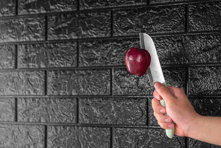 Floating red apple pierced with stainless steel knife with black background