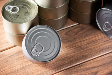 various gold and silver tuna cans superimposed on each other with close view on brown wood