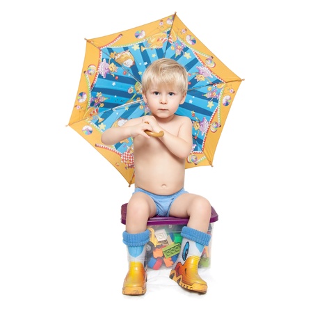 the boy in boots under an umbrella sits on a box with the blocksの写真素材