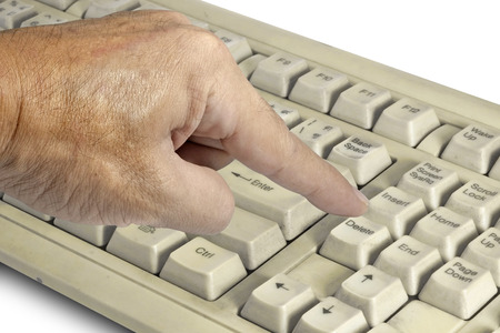 Finger pressing on delete button of old keyboard.