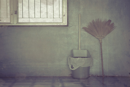 Broom with dustpan and small trash at the wall near the windows, vintage grunge style.の写真素材