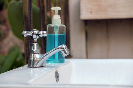 Old and dirty chrome faucet on ceramic washbasin.の写真素材