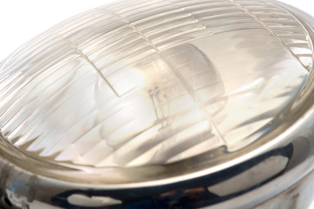 Close up burn out old headlight motorcycle on white background. Select focus on filament.