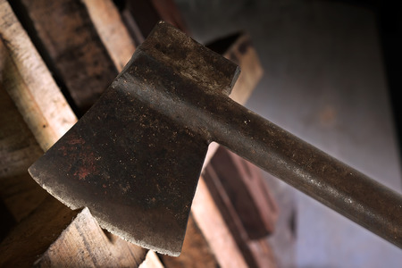 Old and dirty axe on wood. Dark tone.