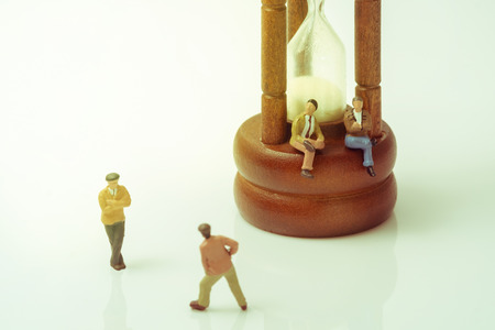 View of miniature toy people with vintage hourglass on white background. Vintage style.の写真素材