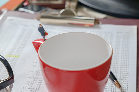 View of miniature toy, businessman standing on red coffee cup.の写真素材