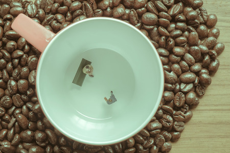 View of miniature toy, businessman talking in red coffee cup. Vintage style.の写真素材