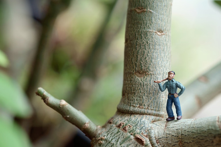 View of miniature toy, lumberman standing on tree. Focus on lumberman.の写真素材