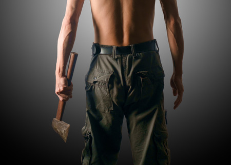 Rear view of man holding axe on gray background. Dark tone.の写真素材