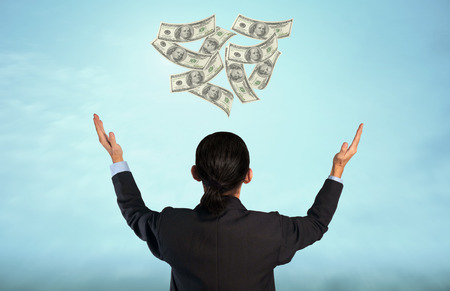 Rear view of businessman and dollars on blue sky background.の写真素材