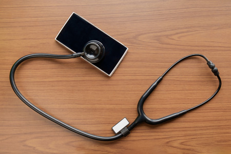 View of stethoscope and smartphone on wood table. Top view. Health concept.の写真素材