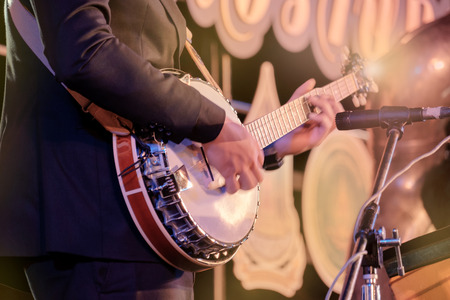 View of musician playing banjo in concert at night. Movement. Shallow depth of field.の写真素材