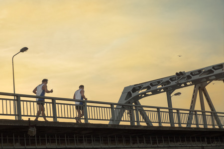 View of young men jogging on the bridge at twilight.の写真素材