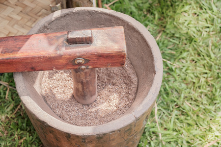 View of wooden mortar pounding rice grain. Shallow depth of field.の写真素材
