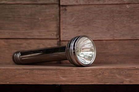 View of old flashlight on dirty wooden shelf. Shallow depth of field.の写真素材