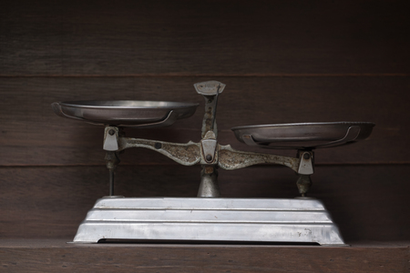 View of old scales on dirty wooden shelf. Dark tone. Shallow depth of field.の写真素材