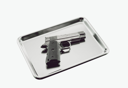 Pistol on stainless tray on white background.の写真素材