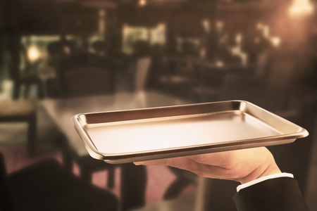 Stainless tray on hand waiter on restaurant background.の写真素材