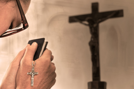 View of prayer with bible and necklace jesus on cross in hands. Digital retouch.の写真素材