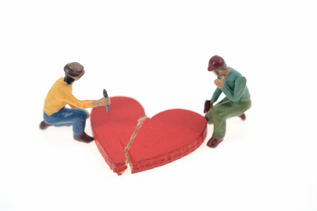 Broken red heart with worker on white background.の写真素材