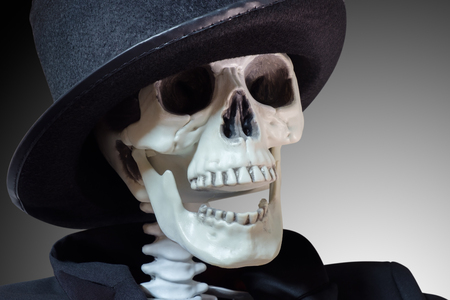 Closeup skeleton with magician hat on gray background.の写真素材