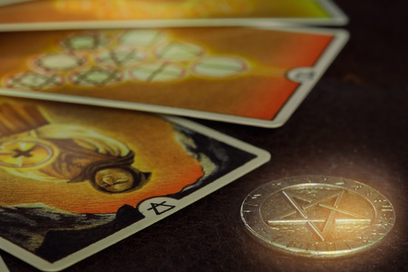 View of pentacle coin and Tarot card (Minor arcana) on the table. Dark tone.の写真素材