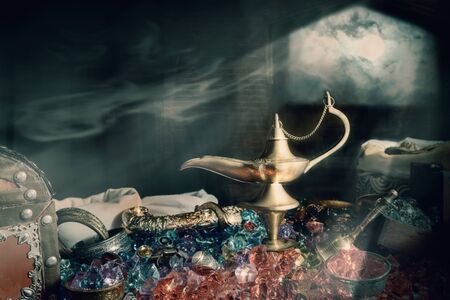 View of aladin lamp and treasure with smoke in the room at night. Dark tone.