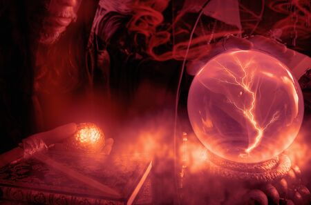 Close up crystal ball with light and wizards in dark room.の写真素材