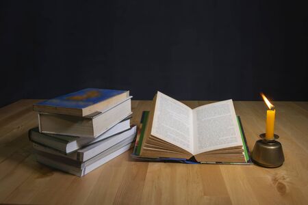 Open book and burning candle on darkの写真素材