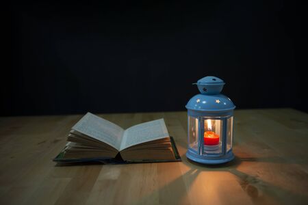 candle lantern and book on a wooden background.  lamp with a burning candle.