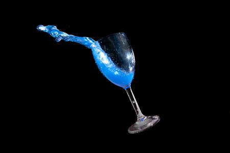 Blue splash water out of a glass on black background.の写真素材