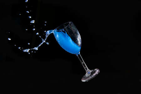 Blue splash water out of a glass on black background.の写真素材