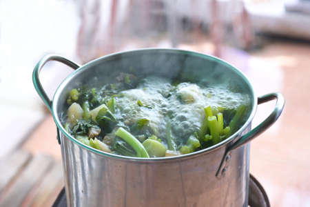 A boiling pot of vegetable soup on top of the stove.の写真素材
