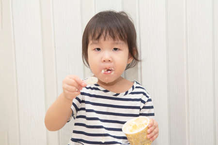 Asian cute toddler girl enjoying her ice cream at home.の写真素材