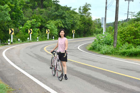 Asian  woman with bicycle on a forest road.の写真素材