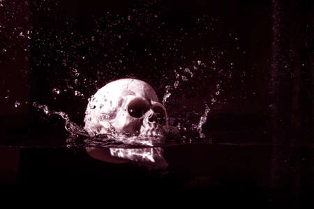 Human plastic skull falling in water isolated on black background.Halloween imageの写真素材