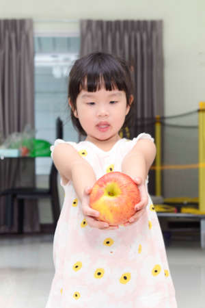 Little Asian girl with a big apple in her handsの写真素材