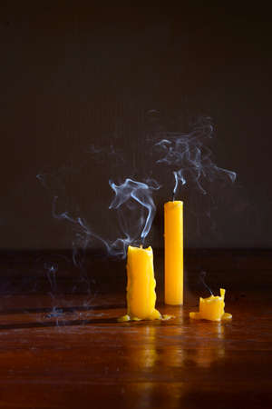 Extinguished candles on wooden table with smooth, white smoke from candles.の写真素材