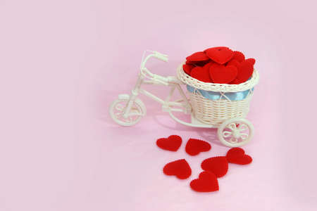 Small toy white bicycle with a basket and red heart shape on pink background. Copy space for textの写真素材