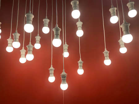 Hanging light bulbs with the depth of field on red backgroundの写真素材