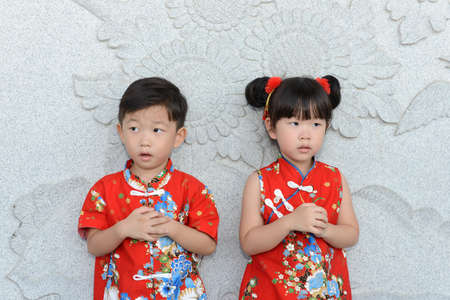 Little Asian boy and girl in Chinese traditional dress to celebrate Chinese New Year..Little asian boy and girl pray and wishing you a happy Chinese New Year.の写真素材