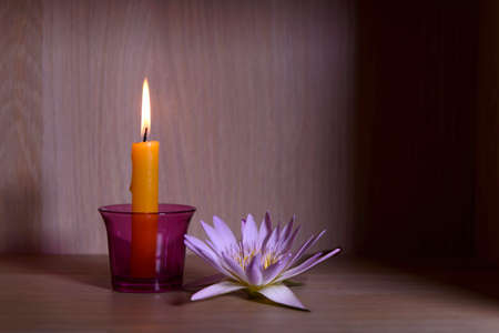 Burning candles and beautiful waterlily on a wooden floor.の写真素材