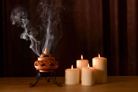 incense burning in an incense burner with candles on the table for praying Buddha or Hindu gods to show respect.Religion concept.の写真素材