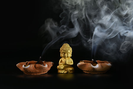 Close-up of a little Buddha statue with the smoke of an extinguished candle  on the back backgroundの写真素材