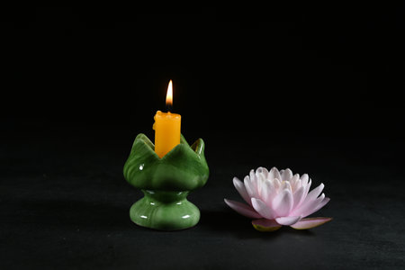 Beautiful water lily with a burning candle on a dark backgroundの写真素材