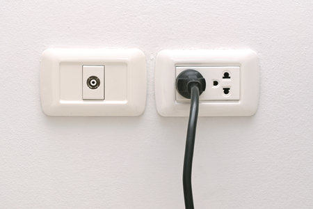 Power plug connected to wall outlet in room