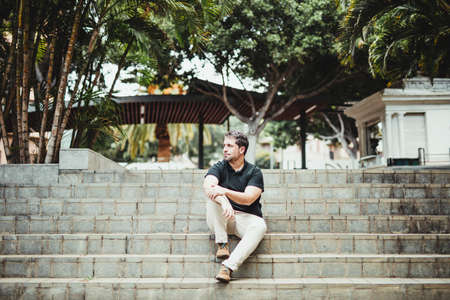 Man sitting on a staircase in a city park with a waiting attitude
